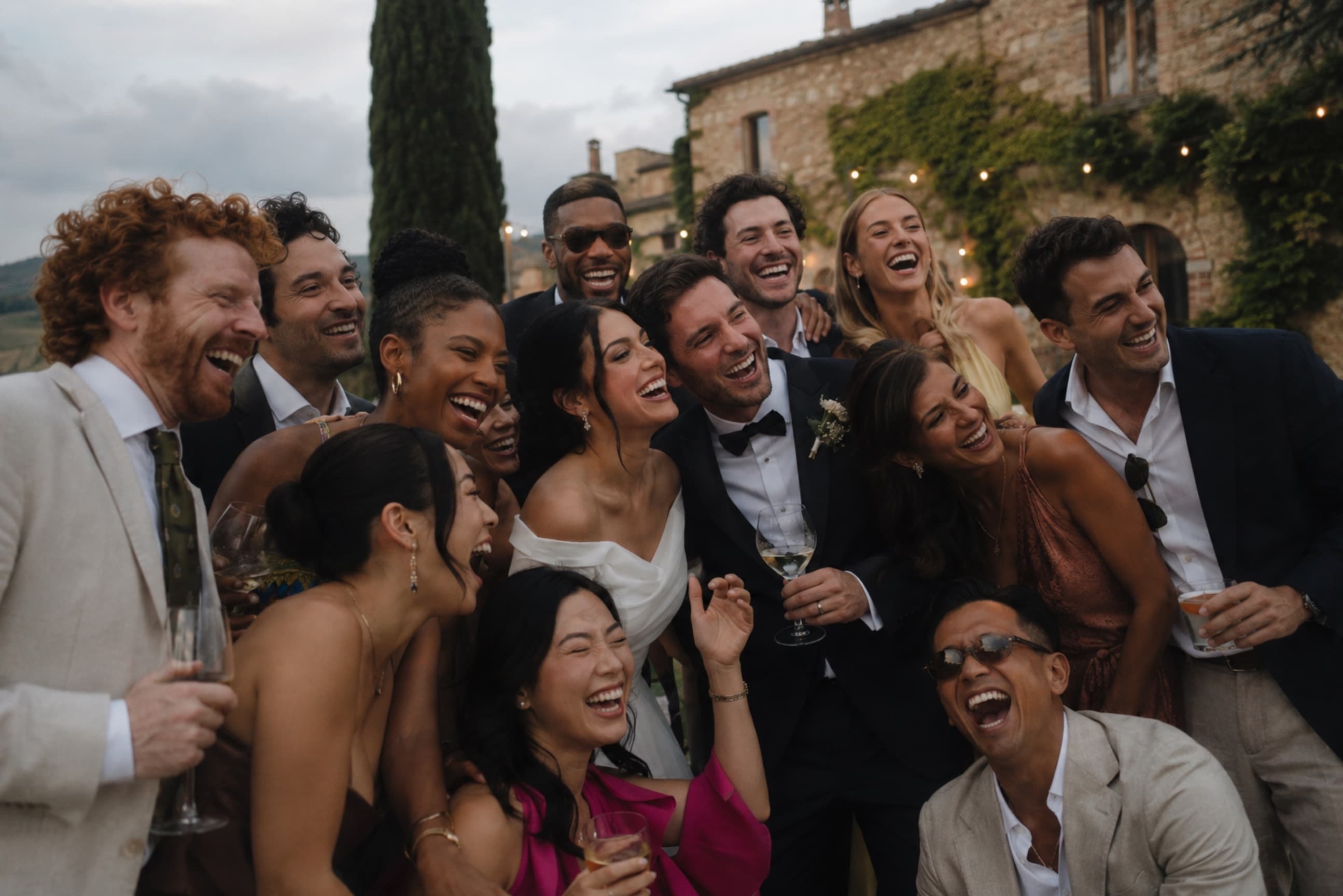 Diverse mixed-age wedding guests laughing together outdoors at dusk