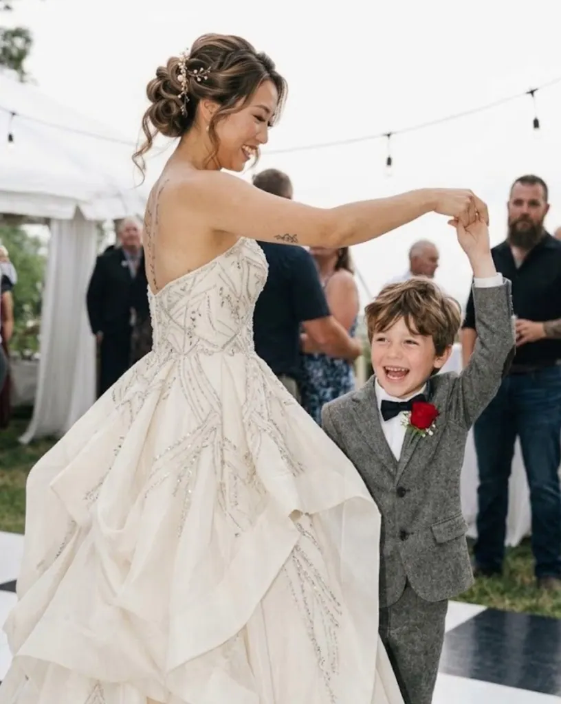 Bride dancing with a laughing child on a checkered reception dance floor