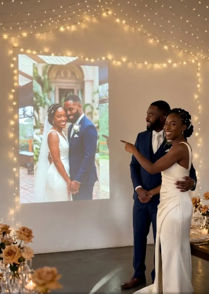 Newlyweds pointing at a projected photo of themselves during their wedding reception