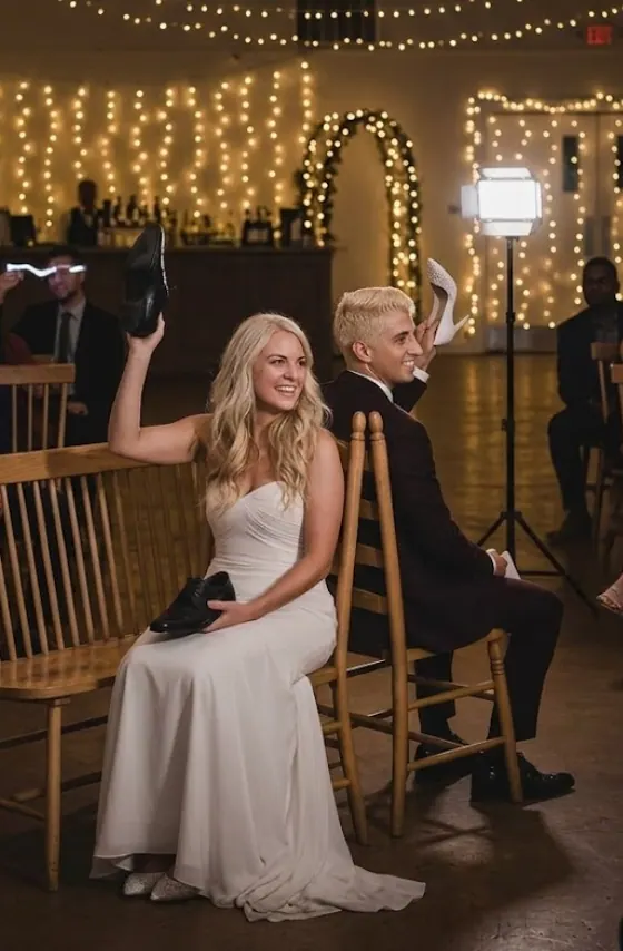 Bride and groom playing the shoe game back to back, holding each other's shoes